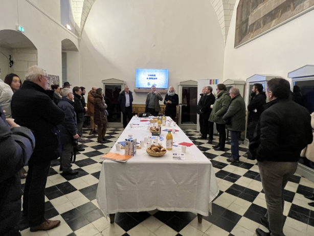 Photo de nombreuses personnes autour d'une table sur laquelle sont posées des viennoiseries