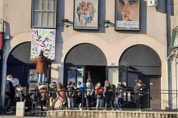 Photo des enfants devant le cinéma qui regardent leur affiche en train d'être posée