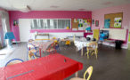 Photo de la salle créative de l'accueil de loisirs avec différentes tables et des peintures accrochées au mur