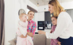 Photo de 2 femmes souriantes aux côtés de 2 enfants, dans un salon avec en arrière-plan une cuisine