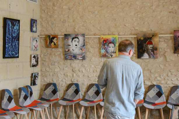 Photo d'un homme devant une exposition de peintures